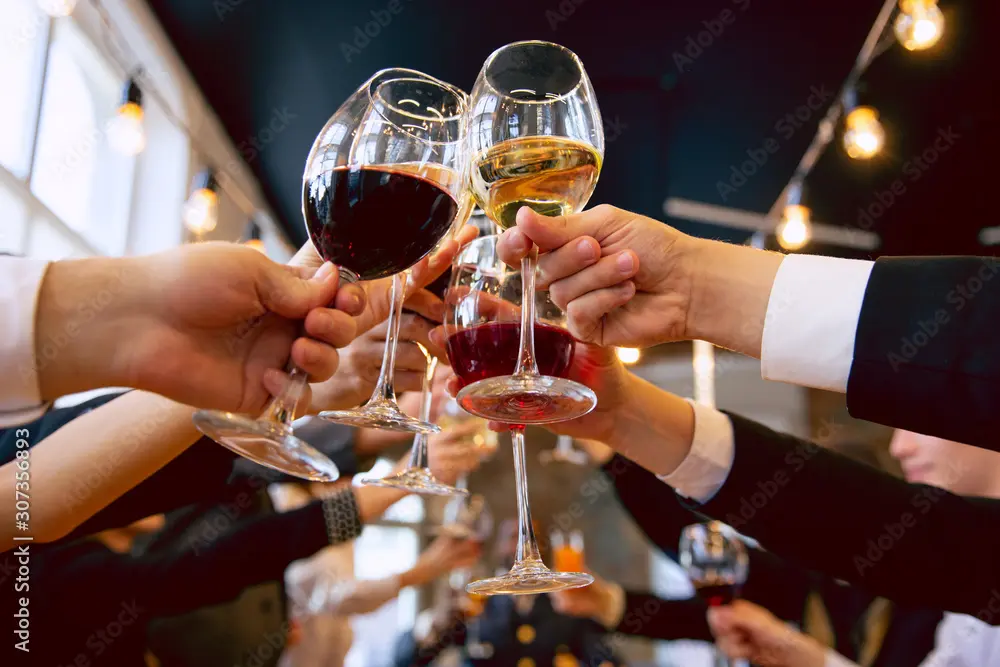 Hands holding glasses of red and white wine for a toast at a celebration at The Yard in Seneca, SC.